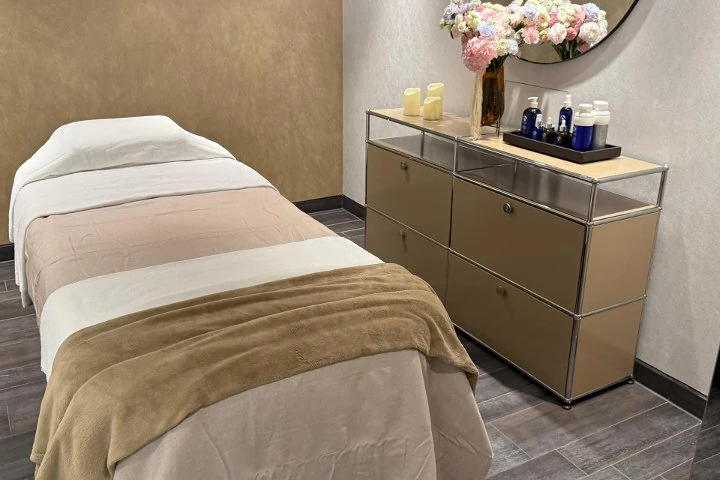 Warmer Spa-Behandlungsraum mit Liege, Kerzen und Pflegeprodukten